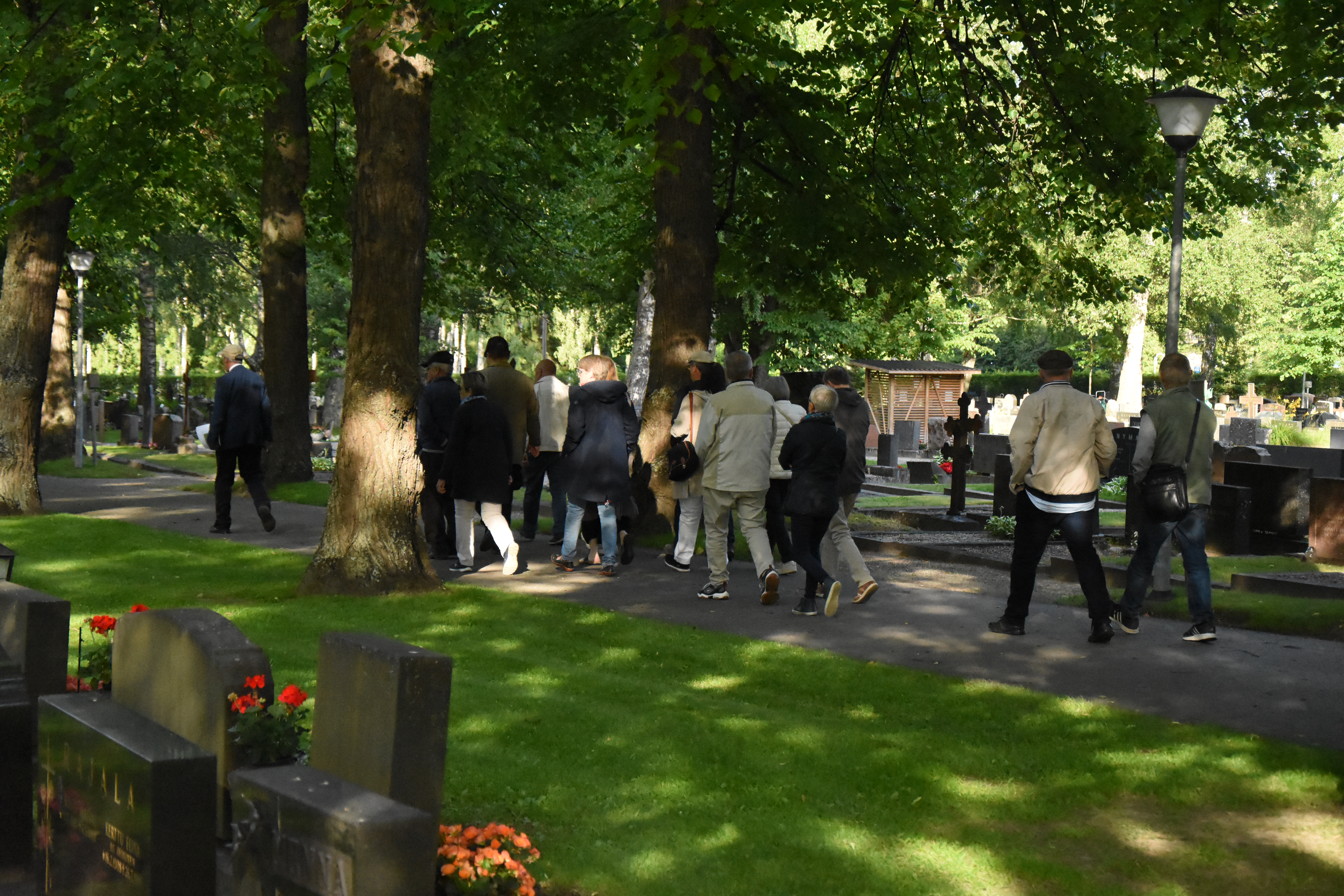 Ihmisiä kulkee ryhmässä hautausmaalla