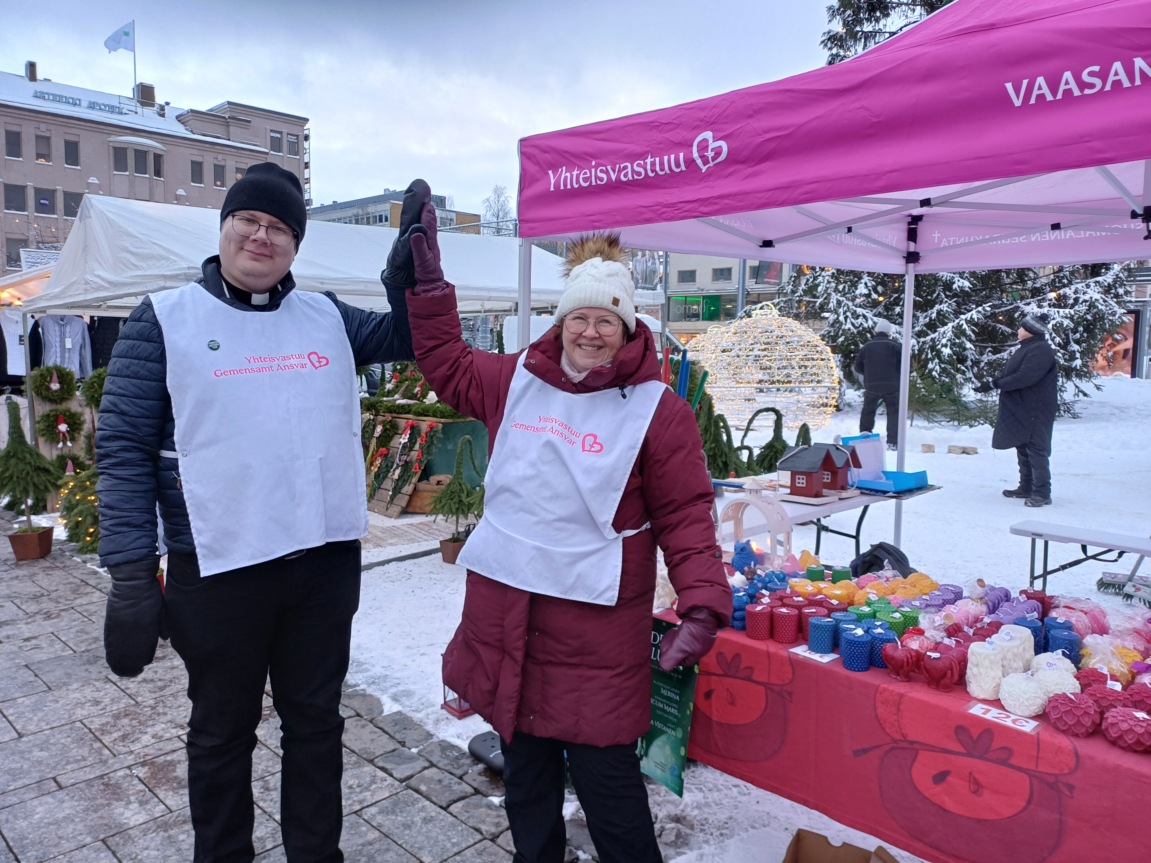 Pinkki katos, työntekijät nostaneet toisen käden yhdessä ylös ja hymyilevät iloisena.