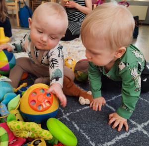 pienet lapset istuvat lattialla leikkien