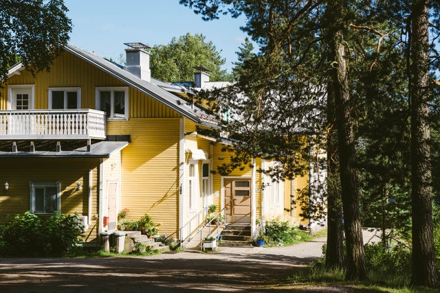 Keltainen puutalo eli Riihon majatalo puiden katveessa.