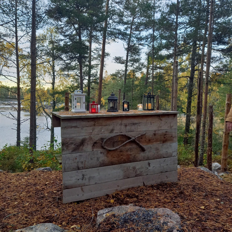 Metsä meri puusta tehty alttari.Alttaripöytää koristaa oleva kala. Alttarilla lyhtyjä.