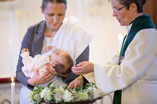 Pappi kastaa vauvan kirkossa.
