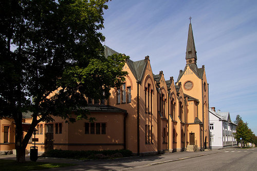 Oranssikellertävä kirkko, jossa tummanruskea peltikatto