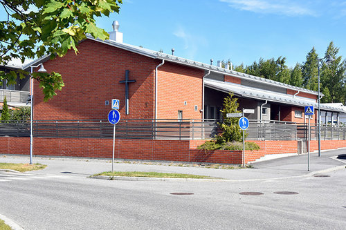 Metsäkallion seurakuntakoti Punainen tiilirakennus jossa risti seinällä