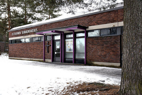 Ristinummen seurakuntakeskus Tummanruskea tiilirakennus. Maassa lunta.