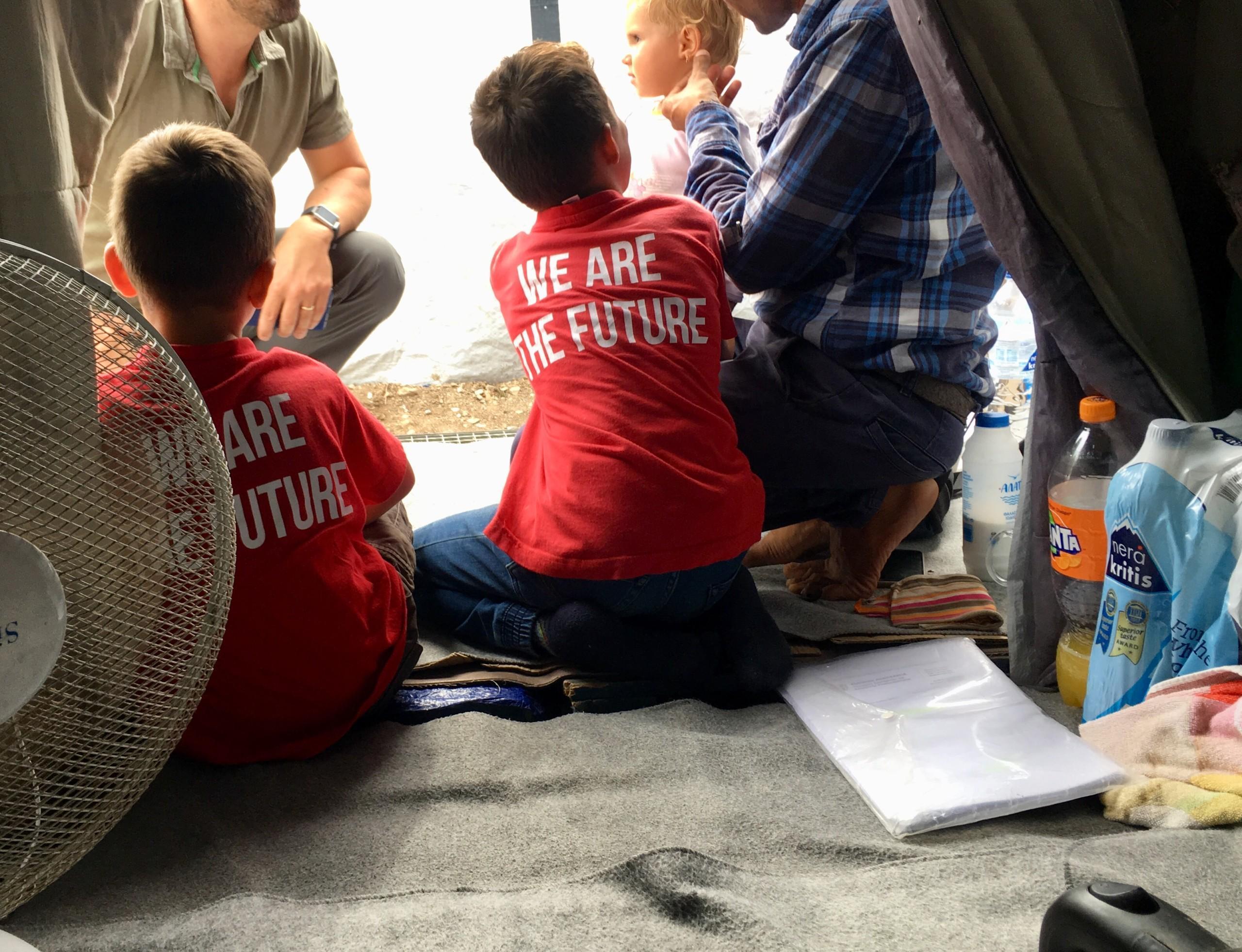 Kreikan pakolaisleirien lapsia, joiden paidan selässä lukee We are Future
