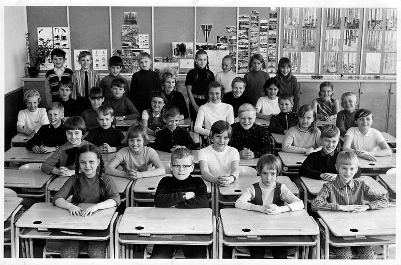 Mustavalkoisessa kuvassa koululaisia pulpeteissa, kuva ehkä 50-luvulta.