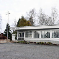 Siltaranta Matala valkoinen puurakennus, jossa isot ikkunat. Pihalla korkea valkoinen risti.